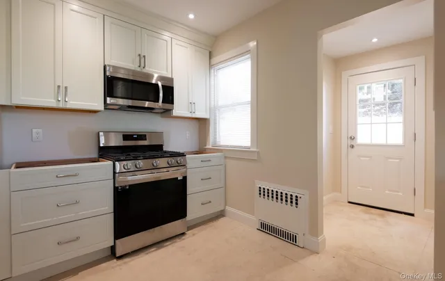 a kitchen with stainless steel appliances granite countertop white cabinets and window