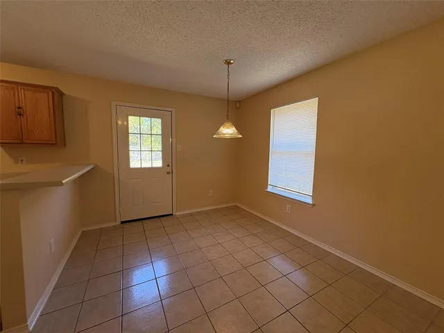 a view of an empty room with window and chandelier fan