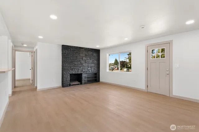 an empty room with windows and fireplace