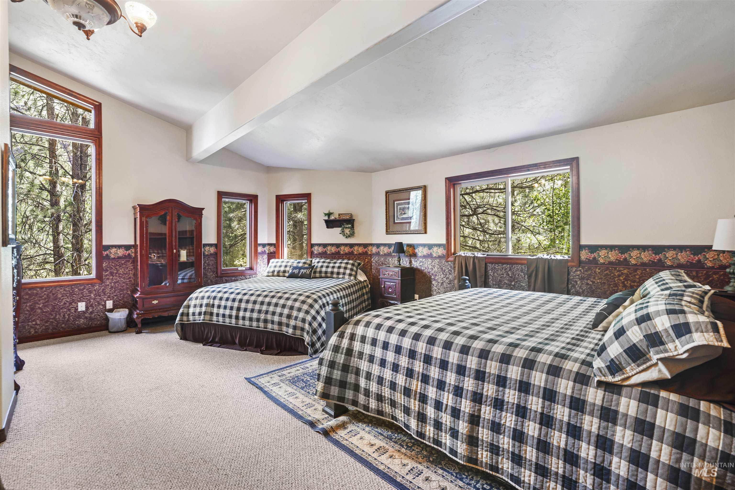 224 Dakota Road Mountain Home, ID 83647 - Photo 22 of 50 Spacious interior featuring vaulted ceilings and multiple windows showcasing a wooded backdrop