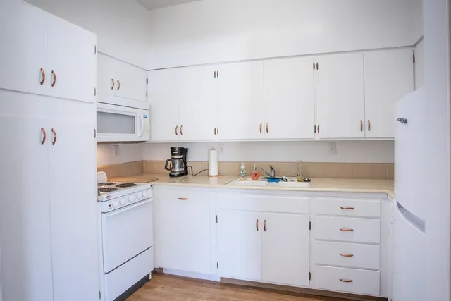 a kitchen with white cabinets and white appliances