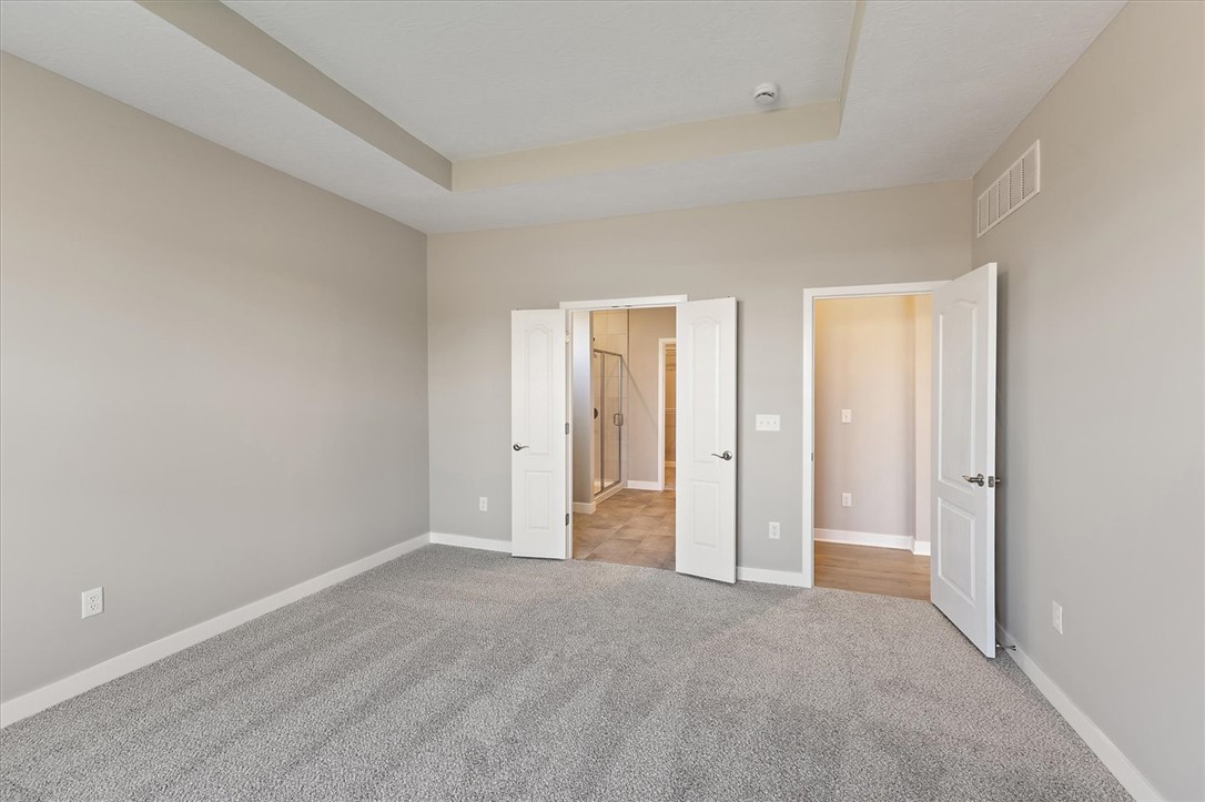 407 South Landon Lane Springfield, OH 45502 - Photo 10 of 30 A spacious primary bedroom features soft carpeting, a tray ceiling, and convenient access to an en-suite bathroom.