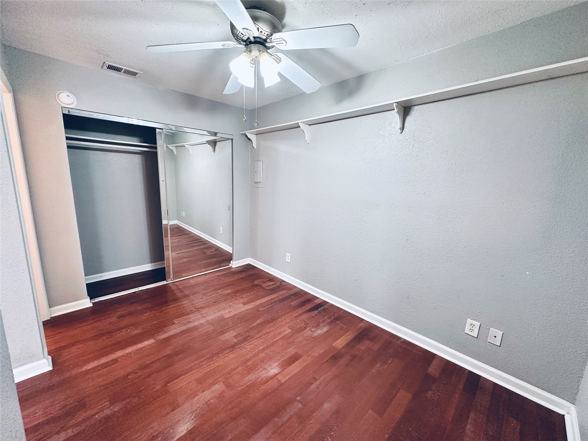 2500 Burleson Road, Unit 209 Austin, TX 78741 - Photo 16 of 24 Well-lit room featuring rich hardwood flooring and a functional closet with mirrored doors.