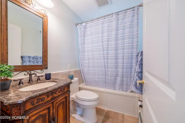 a bathroom with a granite countertop bathtub sink vanity mirror and toilet
