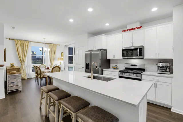 a kitchen with a sink a stove a refrigerator cabinets and a dining table