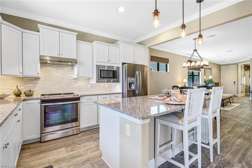 20321 Corkscrew Shores Boulevard Estero, FL 33928 - Photo 3 of 38 a kitchen with stainless steel appliances granite countertop a kitchen island hardwood floor sink and stove