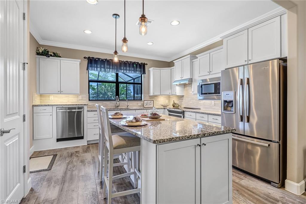 20321 Corkscrew Shores Boulevard Estero, FL 33928 - Photo 9 of 38 a kitchen with stainless steel appliances granite countertop a refrigerator a sink dishwasher a s stove top oven a large window with white cabinets and wooden floor