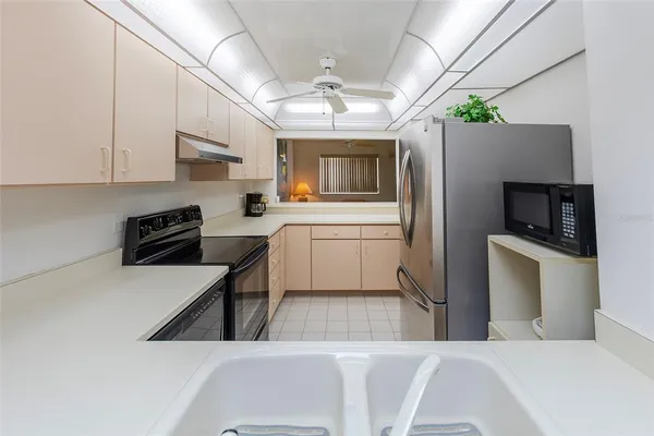 a kitchen with a refrigerator a stove a microwave a sink dishwasher and white cabinets with wooden floor