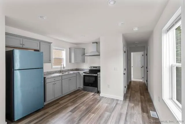 a kitchen with a refrigerator a stove top oven and wooden floor