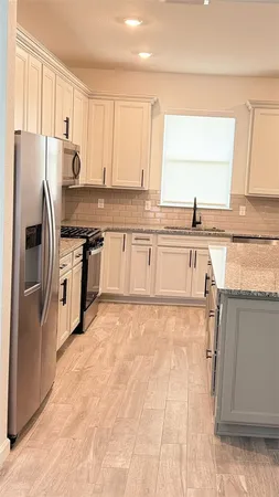 a kitchen with granite countertop a refrigerator sink and cabinets