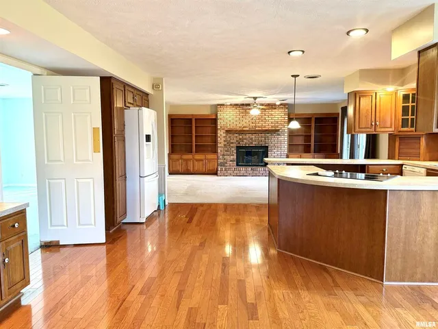 a large kitchen with stainless steel appliances granite countertop a refrigerator a stove and a wooden floors