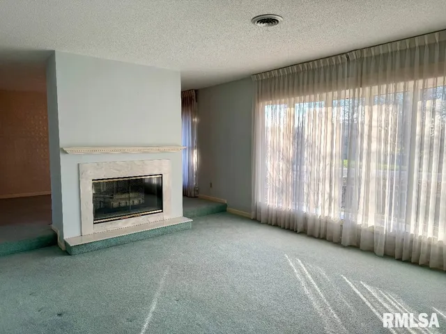 a view of an empty room with a fireplace and a window