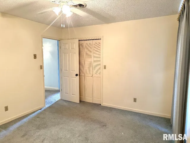 an empty room with a chandelier fan and wooden floor