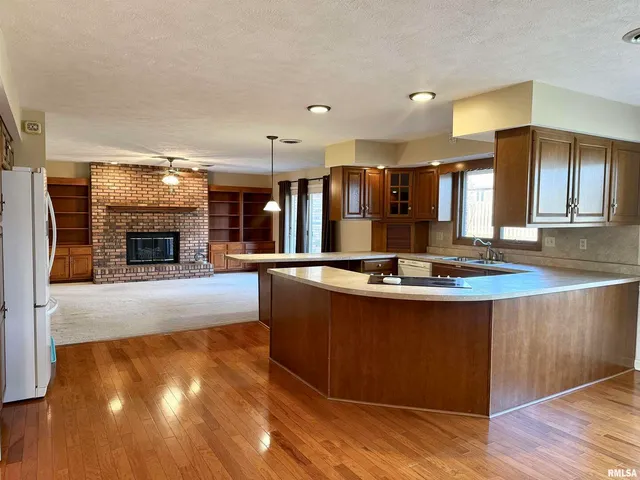 a view of kitchen with kitchen island a sink wooden floor and a living room view