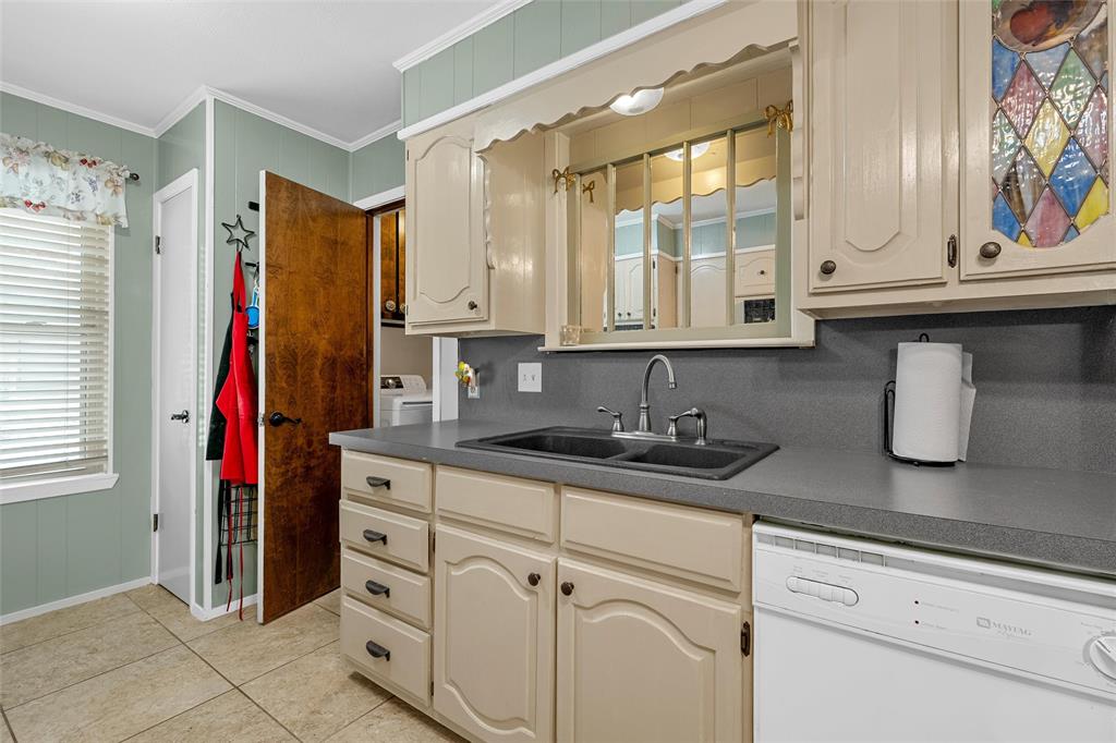 1038 South Old Robinson Road Robinson, TX 76706 - Photo 11 of 36 Kitchen with white dishwasher, ornamental molding, dark countertops, light tile patterned floors, and cream cabinets