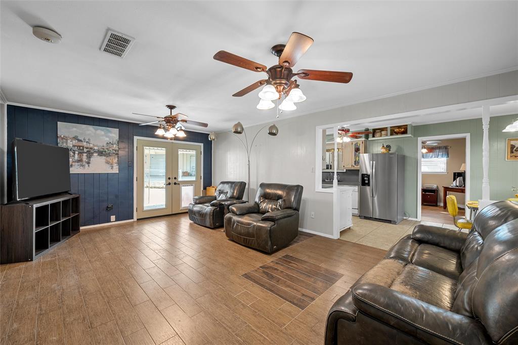 1038 South Old Robinson Road Robinson, TX 76706 - Photo 3 of 36 Living room featuring wooden walls, french doors, light wood-style flooring, ornamental molding, and ceiling fan