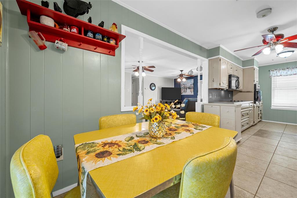 1038 South Old Robinson Road Robinson, TX 76706 - Photo 8 of 36 Dining space featuring ornamental molding, ceiling fan, wooden walls, and light tile patterned flooring