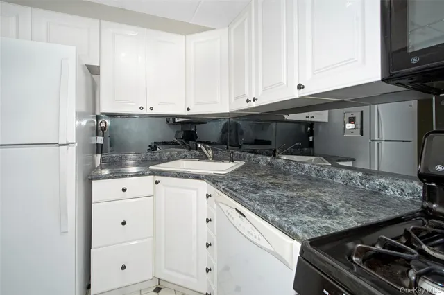 a kitchen with granite countertop a sink stove and refrigerator