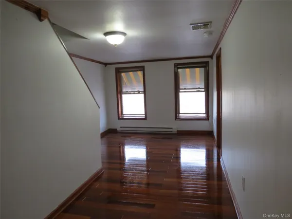 a view of empty room with wooden floor and fan