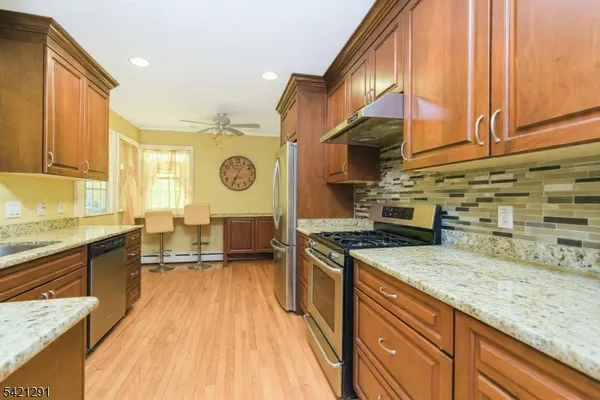 a kitchen with stainless steel appliances granite countertop a sink a stove and a wooden cabinets