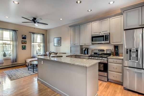 a kitchen with stainless steel appliances granite countertop a stove top oven a sink dishwasher a refrigerator and white cabinets with wooden floor