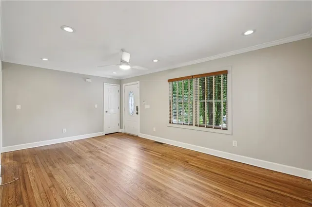 a view of an empty room with wooden floor and a window