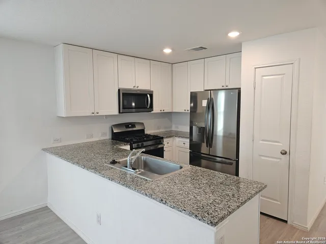 a kitchen with a refrigerator a microwave a sink and cabinets
