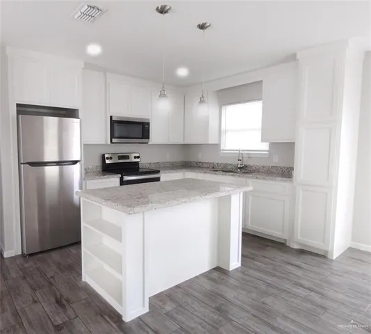 a kitchen with kitchen island granite countertop stainless steel appliances a refrigerator microwave and stove