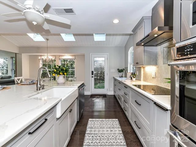 a large kitchen with stainless steel appliances kitchen island granite countertop a large counter top a stove and a sink