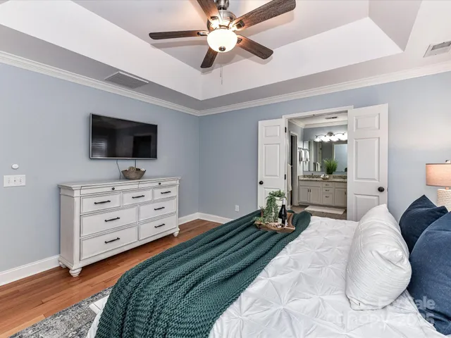a bedroom with a bed a flat screen tv and a chandelier