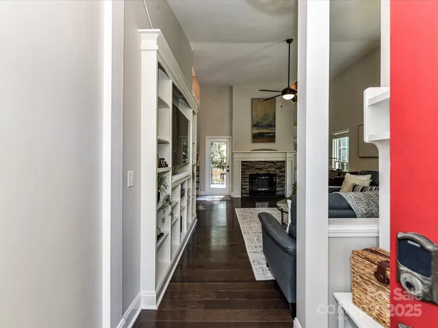 a view of a hallway with wooden floor and a living room