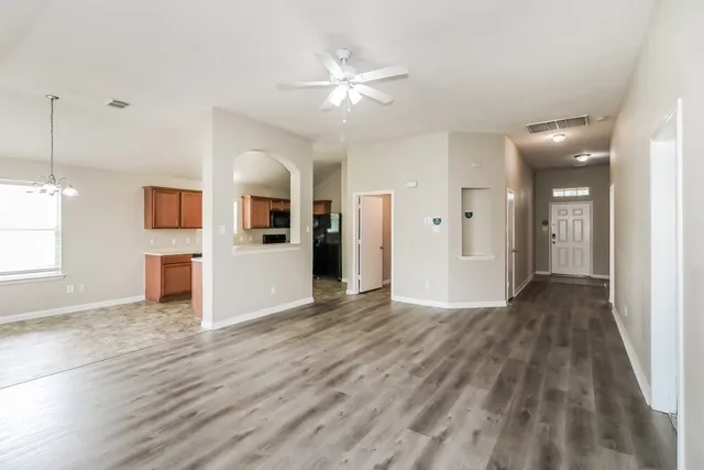 an empty room with wooden floor and a kitchen