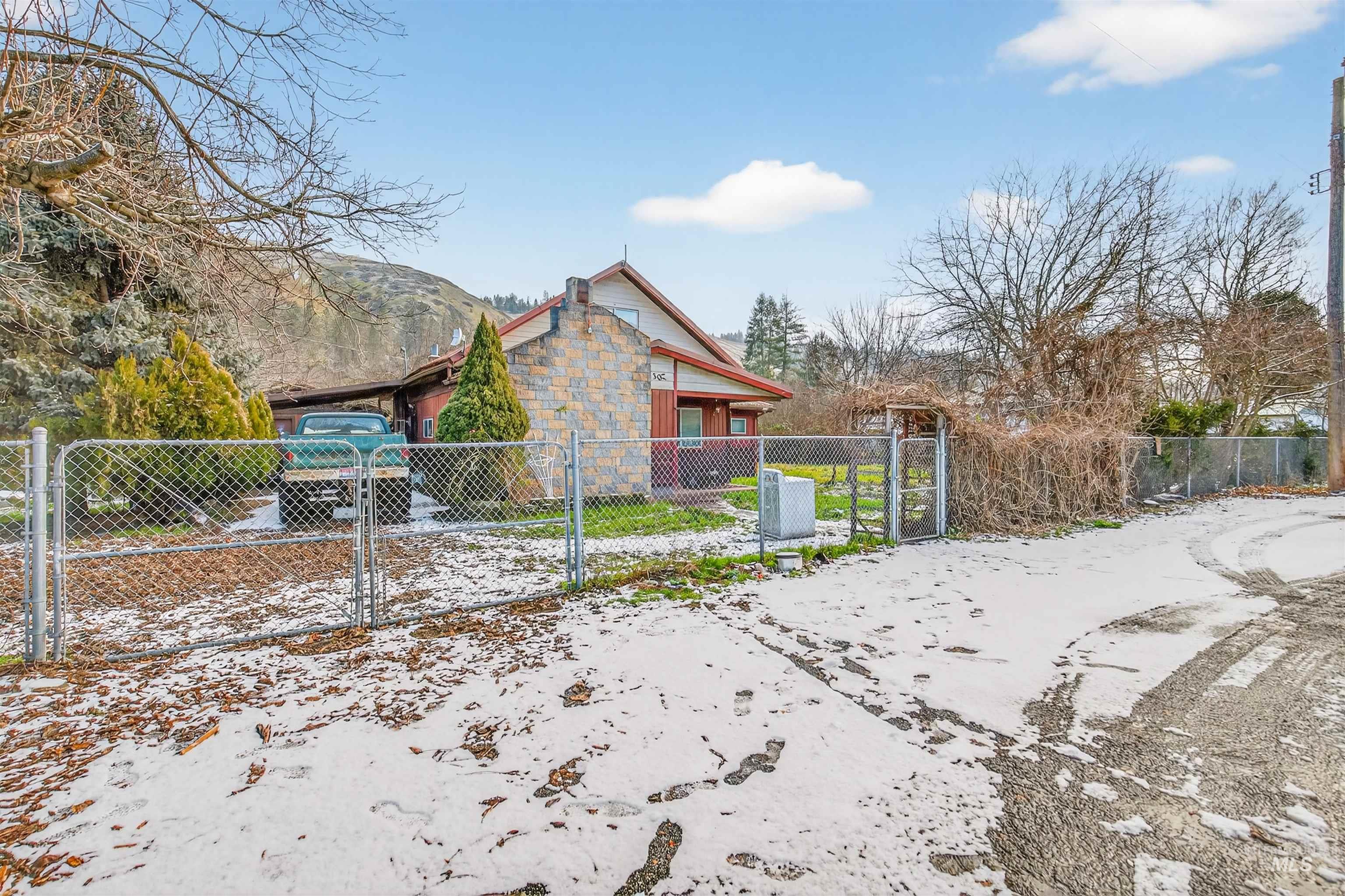 307 Esther Street Kooskia, ID 83539 - Photo 2 of 37 View of snow covered exterior featuring a gate and a fenced front yard