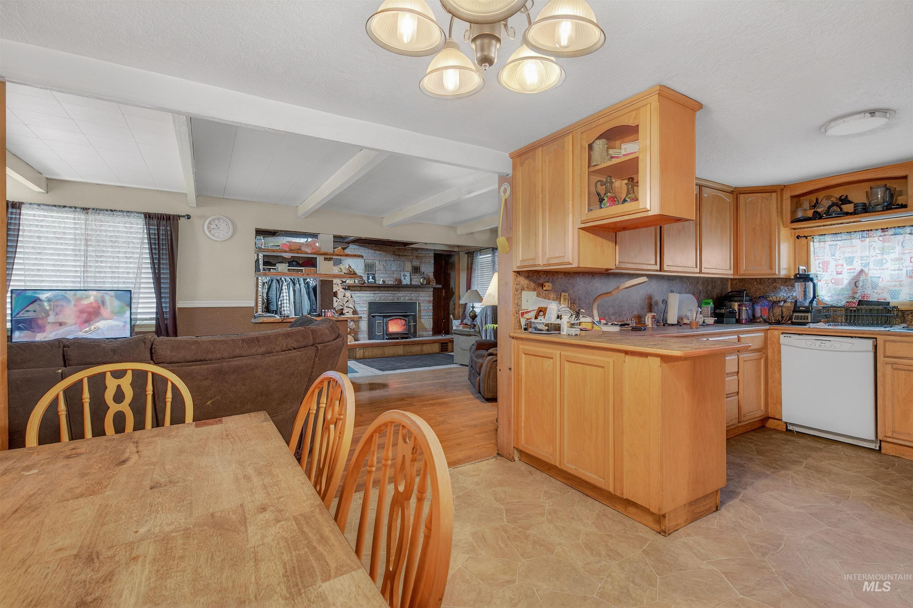 307 Esther Street Kooskia, ID 83539 - Photo 37 of 37 Kitchen with open floor plan, white dishwasher, a glass covered fireplace, light brown cabinets, and a peninsula