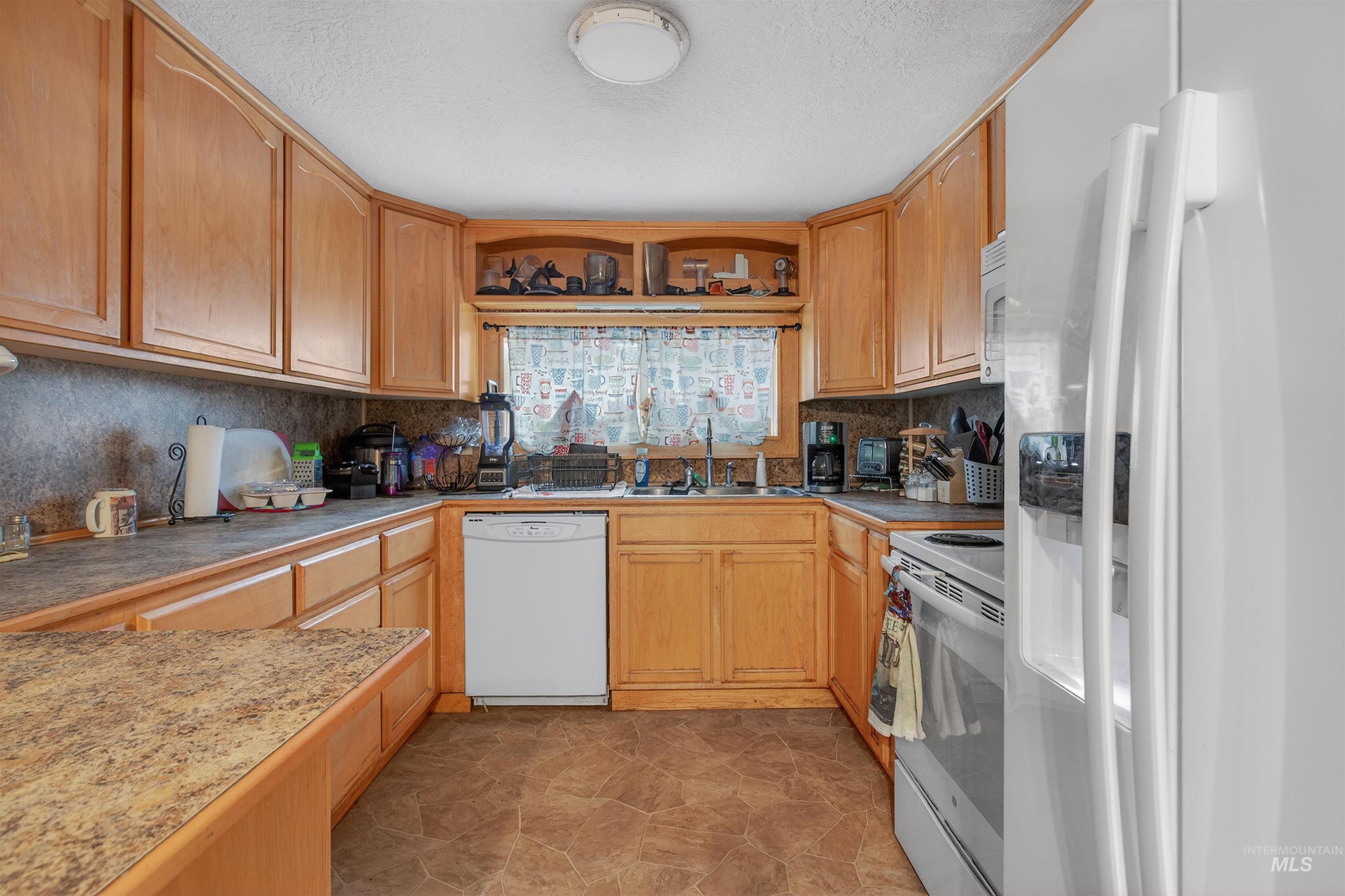 307 Esther Street Kooskia, ID 83539 - Photo 7 of 37 Kitchen with white appliances, a textured ceiling, open shelves, and tasteful backsplash