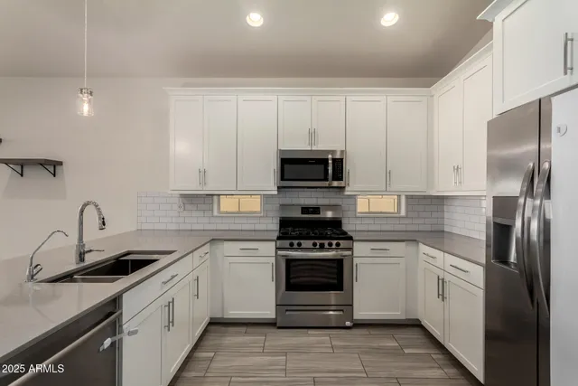 a kitchen with white cabinets stainless steel appliances and a sink