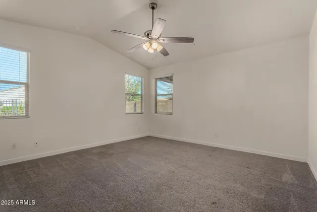 an empty room with windows and chandelier fan