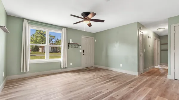 a view of empty room with wooden floor and fan