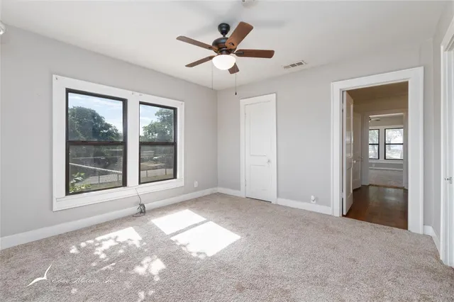 an empty room with windows and ceiling fan