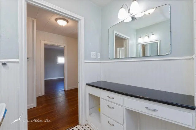 a view of a hallway with wooden floor and cabinet