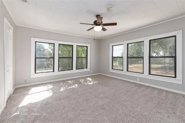 a view of an empty room with a window and a kitchen