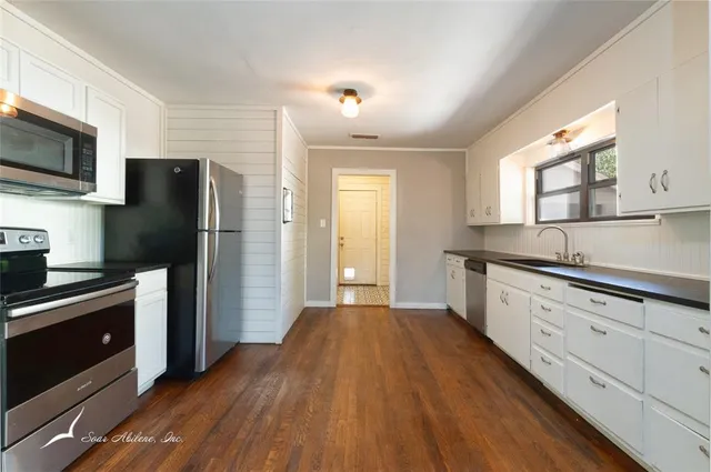 a kitchen with granite countertop a refrigerator stove and sink