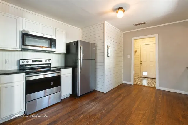 a kitchen with granite countertop a refrigerator and a stove top oven
