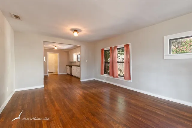 a view of empty room with wooden floor and window