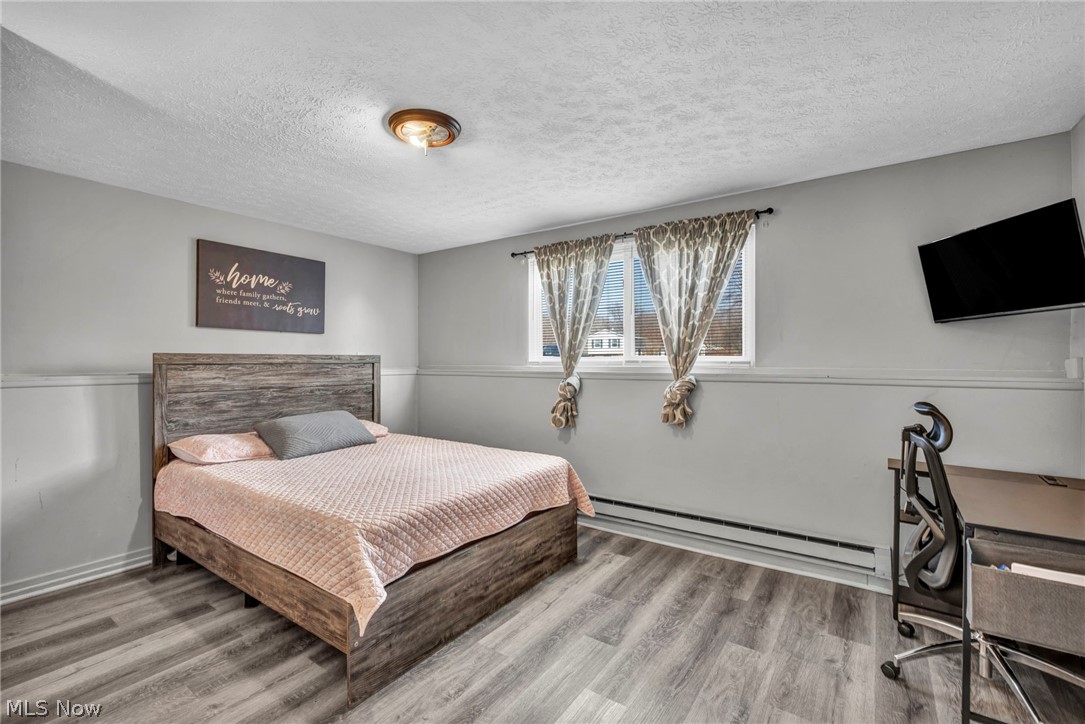 54 Park Road Painesville, OH 44077 - Photo 18 of 38 Bedroom featuring a textured ceiling, baseboard heating, and light wood-style floors