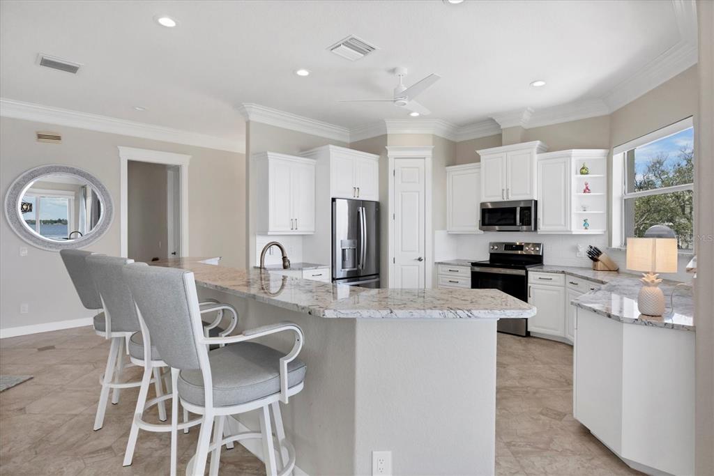 4111 North Beach Road Englewood, FL 34223 - Photo 24 of 87 a kitchen with stainless steel appliances granite countertop a stove top oven a sink dishwasher a dining table and chairs with wooden floor