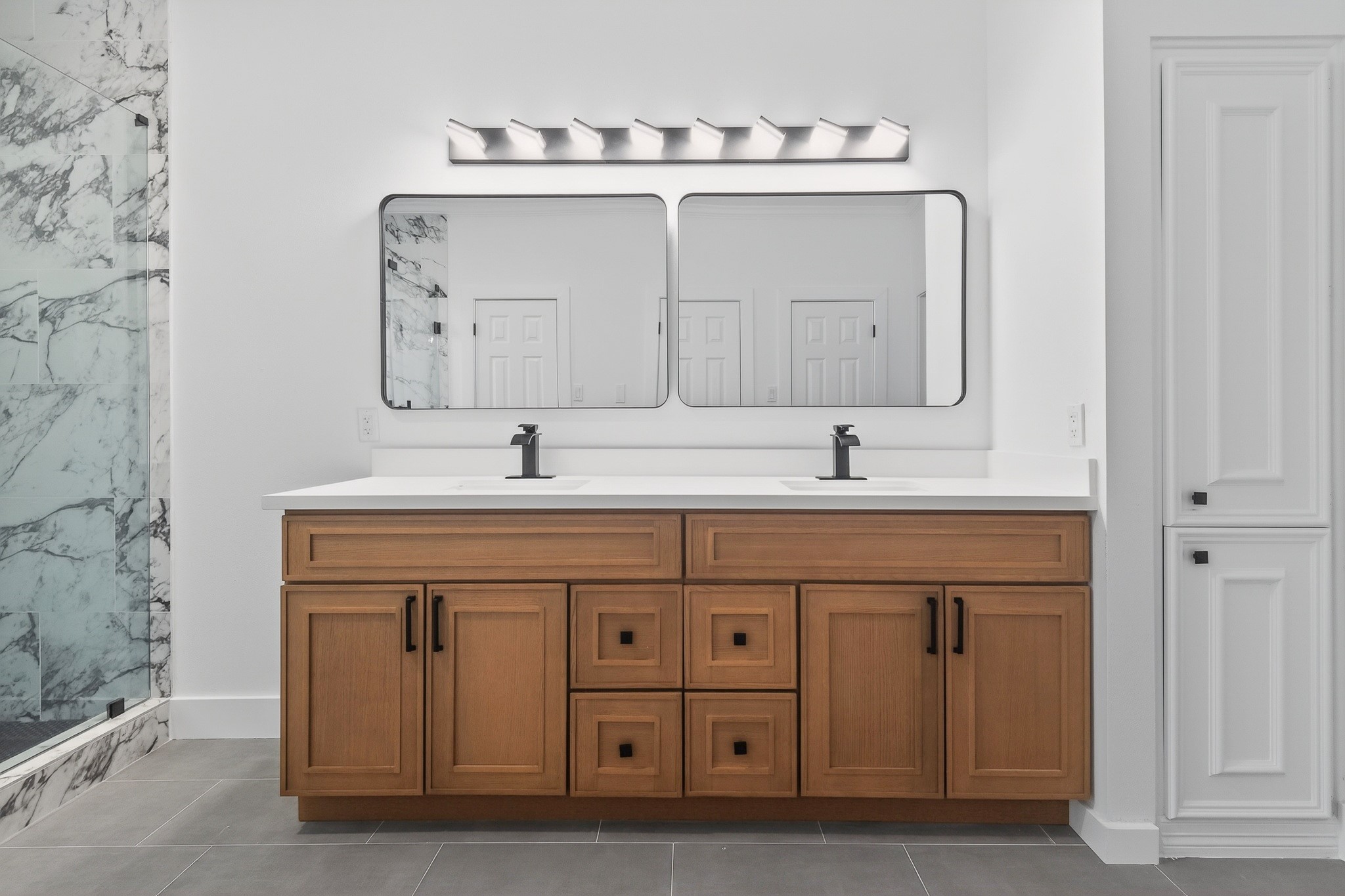 523 Rampart Lane Conroe, TX 77302 - Photo 19 of 41 Beautifully remodeled primary bath vanity showcasing custom cabinetry, sleek quartz countertops, dual sinks, designer mirrors, and sophisticated black accents for a spa inspired experience.