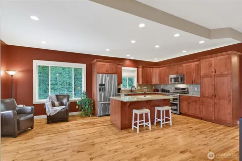 a kitchen with stainless steel appliances granite countertop a stove top oven a sink dishwasher and cabinets with wooden floor