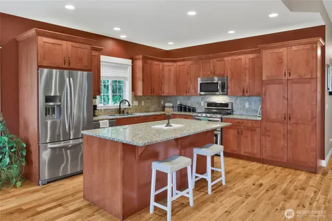 a kitchen with kitchen island granite countertop wooden cabinets a refrigerator and a stove top oven
