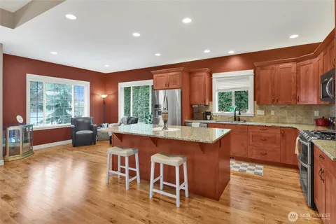 a kitchen with stainless steel appliances granite countertop wooden cabinets a stove and a wooden floors
